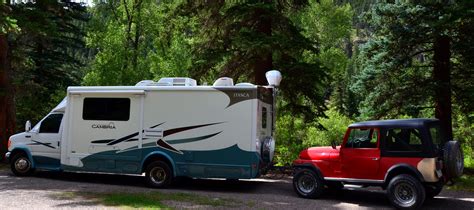 A Truck Towing A Camper In The Woods