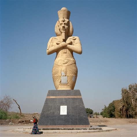 The Large Statue Is Next To A Woman With Her Arms Crossed In Front Of It
