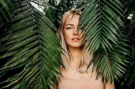 Premium Photo Young Womans Face Surrounded By Tropical Leaves Closeup Portrait Of