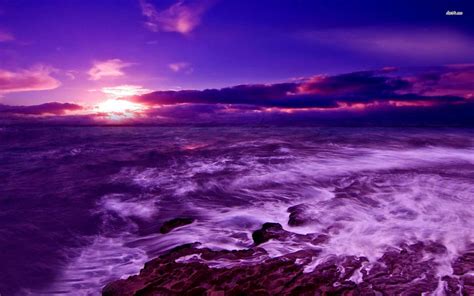 The Sun Is Setting Over The Ocean With Rocks In The Foreground And