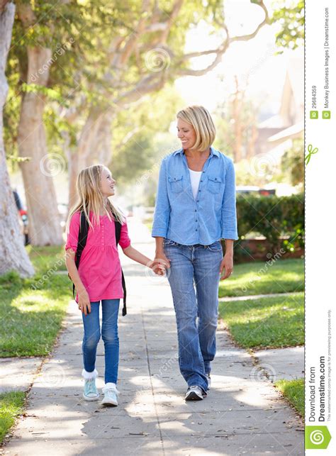 Mother And Daughter Walking To School On Suburban Street