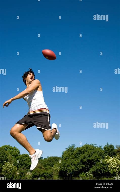 Mann springt mit ovalen Ball im Park spielen Stockfotografie - Alamy