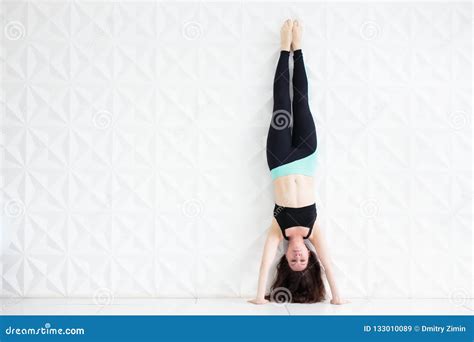 Young Brunette Woman Doing A Handstand Over A White Wall Stock Image