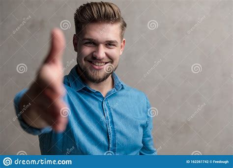 Young Casual Man Welcoming And Reaching For A Handshake Stock Photo