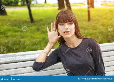 Young Woman In Park Holding A Hand Near Your Ear The Concept Of