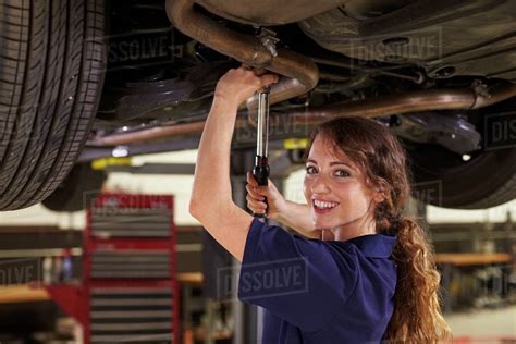 Portrait Of Female Auto Mechanic Working Underneath Car Stock Photo