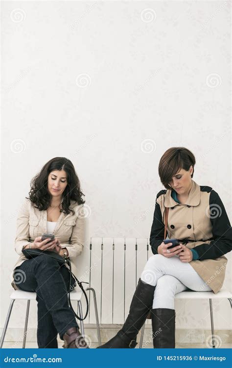 Two Women In Waiting Room Looking Smartphone Serious Stock Photo