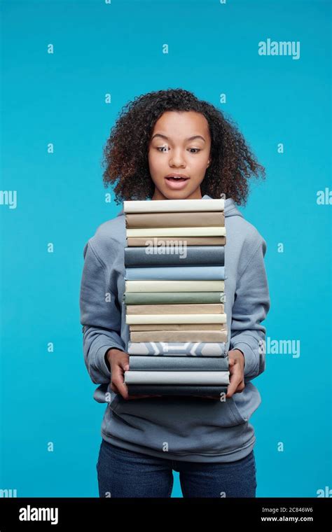 Shocked African American Student Girl In Hoodie Holding Stack Of Text
