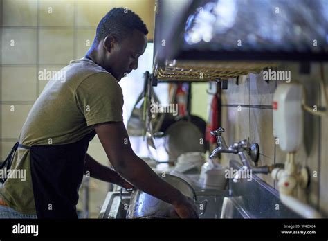 Young Man Washing Dishes In Restaurant Kitchen South Africa Stock