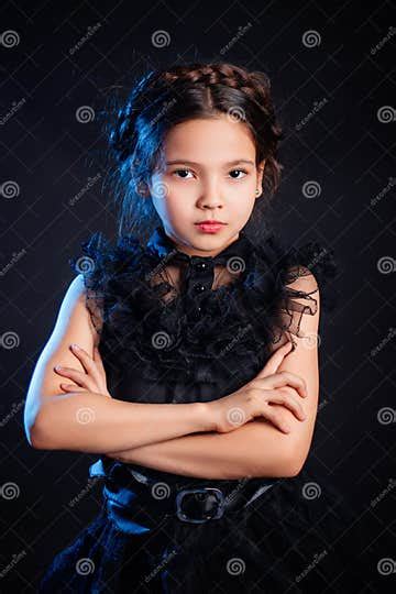 Portrait Of A Little Girl In A Black Dress With A Pigtail Hairstyle On