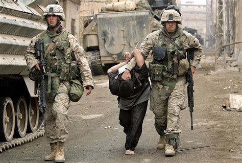 Two Soldiers Walking Down The Street With An Injured Man On His Back