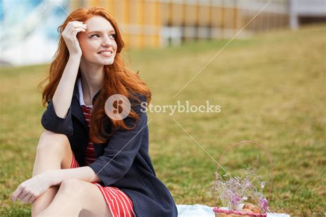 portrait of a smiling happy red head girl having easter picnic with basket and eggs while