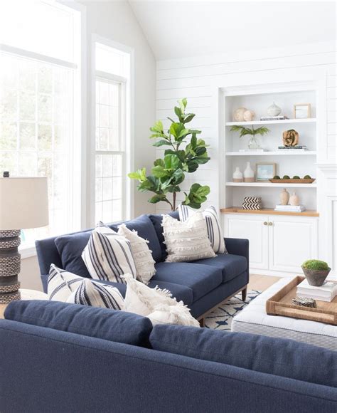 A Living Room With White Walls And Blue Couches In Front Of A Window
