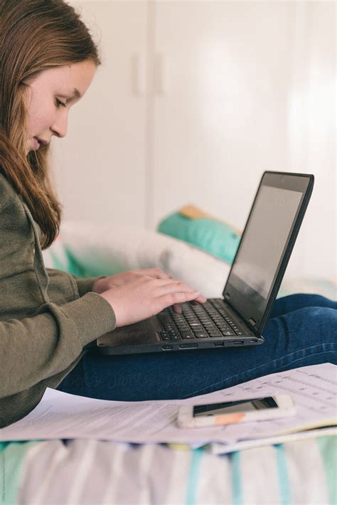 Teen Girl Doing Homework On Her Laptop In Her Bedroom By Stocksy