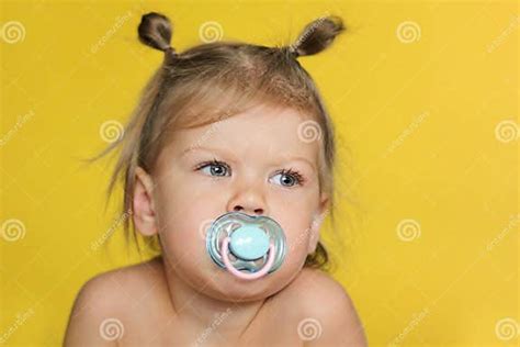 Little Girl With Pacifier In Mouth On Yellow Background Stock Image