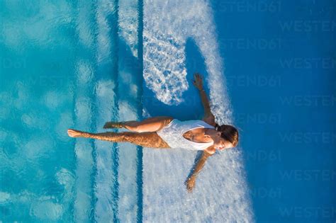 Aerial View Of Woman Laying On The Stairs Of A Swimming Pool In A White