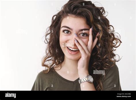 adorable caucasian curly haired female having fun laughing joyfully hold palm face peek through