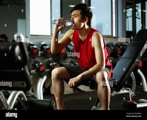Man Sitting On Weight Bench Drinking Bottle Of Water Stock Photo Alamy