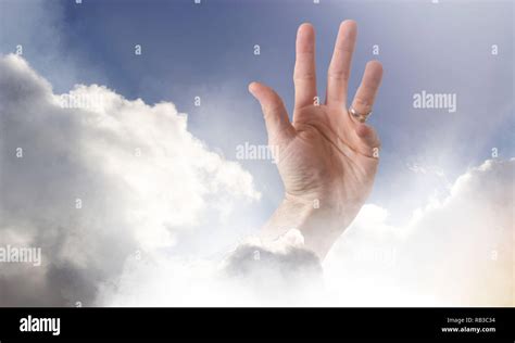 A Hand Reaching Through Clouds Into A Peaceful Blue Sky Representing A