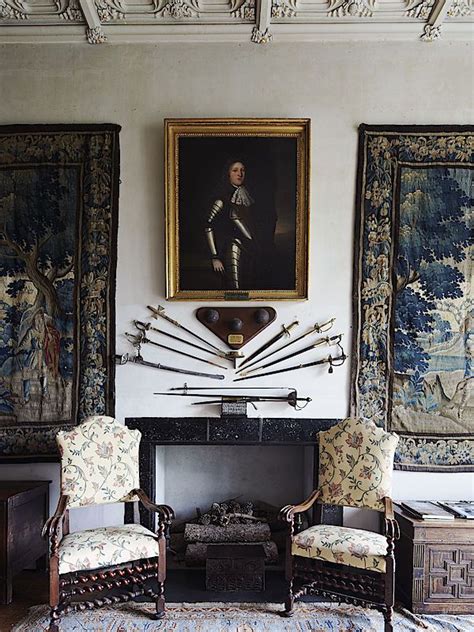 Two Chairs In Front Of A Fireplace With Paintings On The Wall