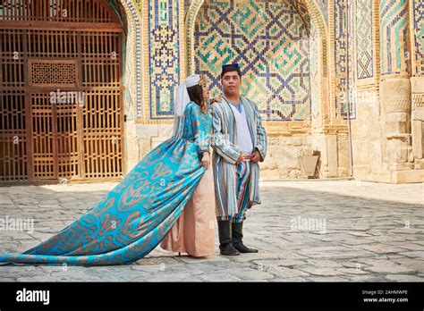 Wedding Couple In Traditional Clothes Posing In Front Of Famous Registan Square Samarkand