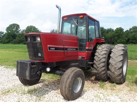 A Red Tractor Parked On Top Of A Gravel Field