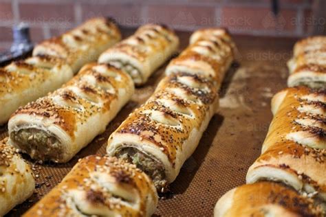 Image Of Close Up Of Freshly Baked Sausage Rolls Lined Up On A Baking