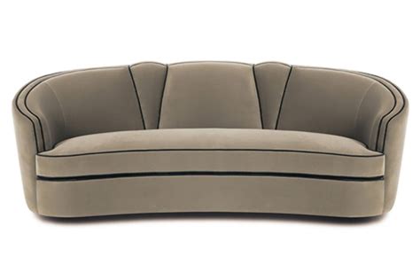 The Curved Couch Is Beige And Has Black Piping On The Back Along With