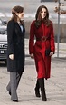 two women in red coats are walking down the street with one holding her ...