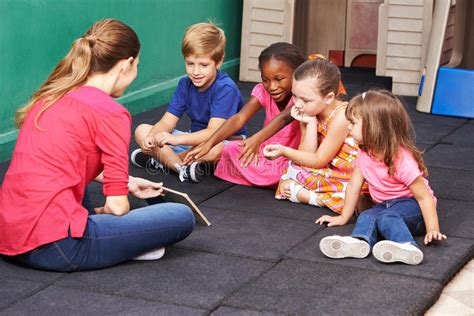 Group Of Kids Talking About Book In Preschool Stock Photo Image Of