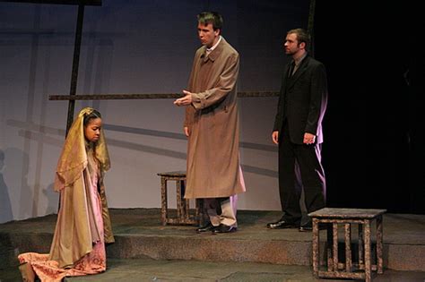 A Girl On Her Knees In Front Of Two Men One Of Whom Is Pointing To Her
