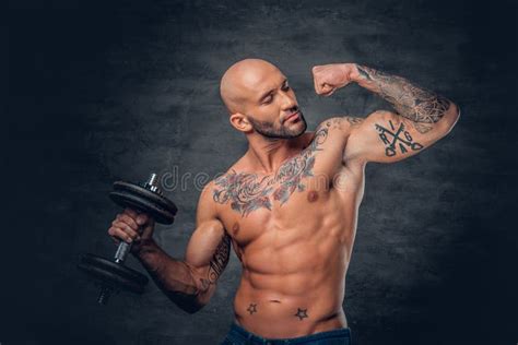 Shaved Head Sporty Male With Tattoos On His Chest And Arms Holds Stock