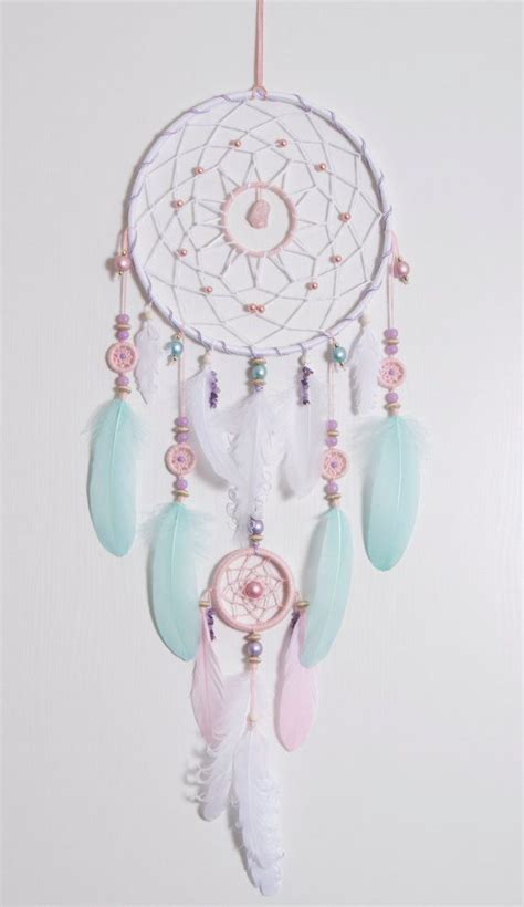 A White Dream Catcher Hanging From The Side Of A Wall With Beads And