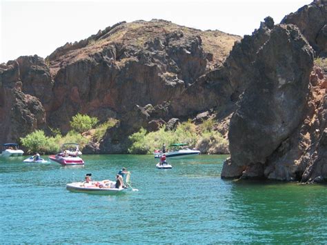 Several People Are In Small Boats On The Water Near Large Rocks And