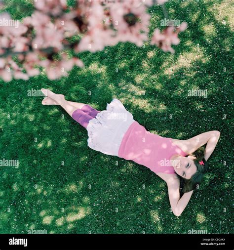 una adolescente recostada en la hierba con las manos detrás de la cabeza mirando hacia arriba