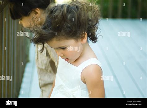 Little Girl Standing Outdoors Looking Down Hair Tousled By Wind Boy