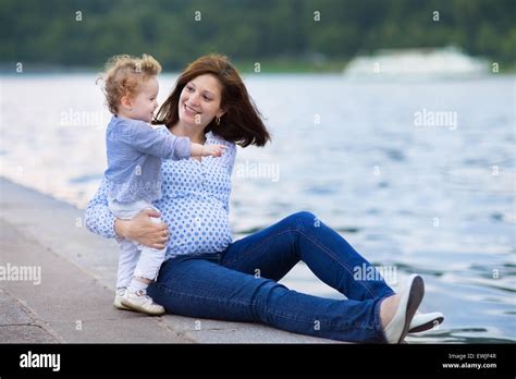 Young pregnant mother and her little baby daughter relaxing at a Stock 
