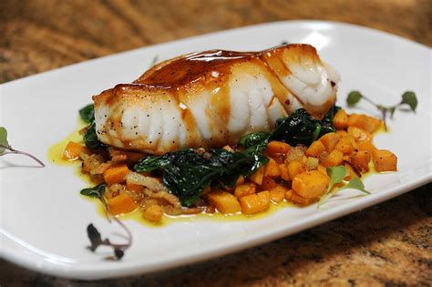 Pan Seared Chilean Sea Bass With Sweet Potato Hash Sautéed Spinach And Orange Soy Reduction