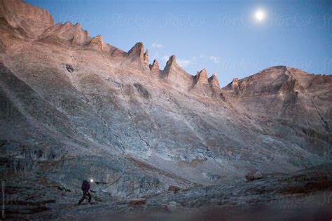 Young Adult Female Hiker Walks In The Moonlight Through Rocky Mountain