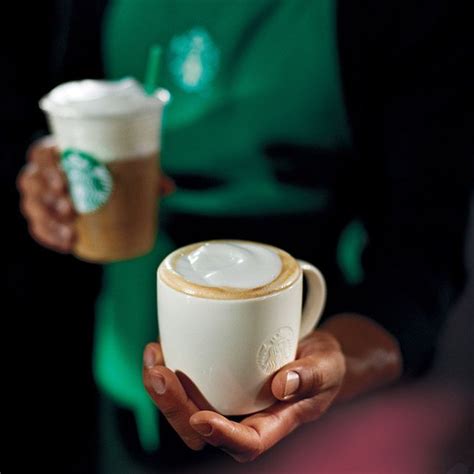 Two People Holding Starbucks Coffee Cups In Their Hands