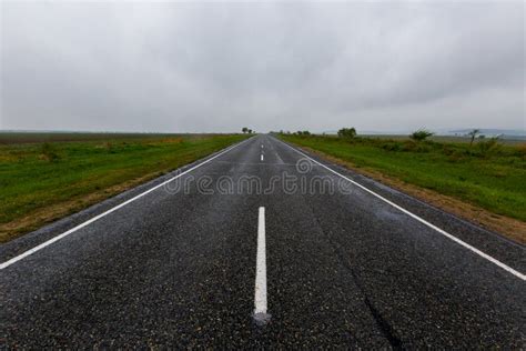 Asphalt Road Receding Into The Distance Among Green Fields Stock Photo