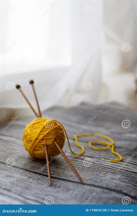 Yellow Colored Wool Ball Knitting Needles On The Wooden Background