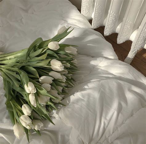 A Bouquet Of White Tulips Laying On A Bed