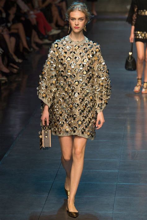 A Model Walks Down The Runway In An Embellished Gold Dress And Matching