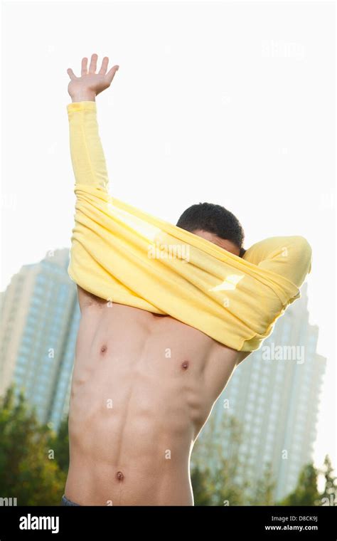 Young Athletic Man Pulling Off Shirt In Park Stock Photo Alamy