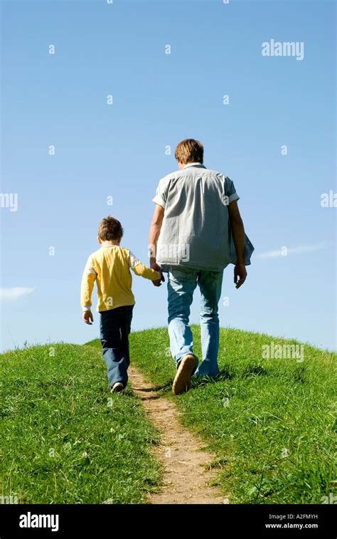 Father Walking Hand In Hand With Son Rear View Stock Photo Alamy