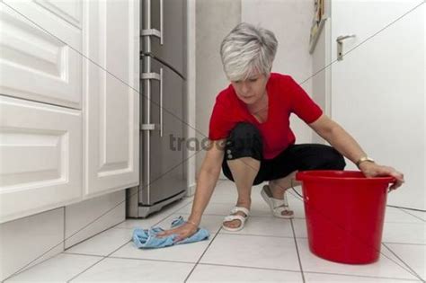 Woman Squatting In The Kitchen To Wipe The Floor Download People