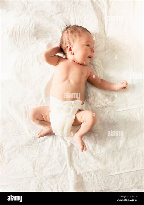Cute Newborn Baby Boy In Diapers Lying On White Sheets On Bed Stock