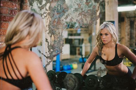 Female Fitness Model Staring At Reflection In Mirror At Gym Holding