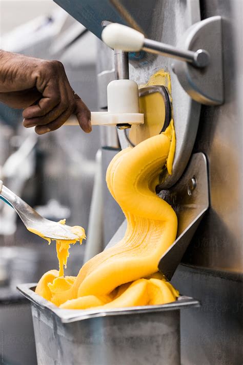 Thick Orange Mango Ice Cream Pouring Out From Industrial Machine By